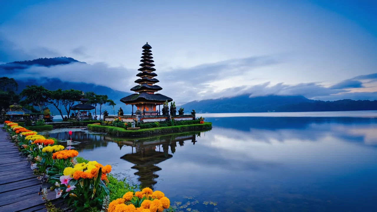 Ulun Danu Beratan Temple floating on calm lake in Bali highlands, morning mist over water, mountains in background, flower offerings near temple steps, cool blue tones, realistic photography